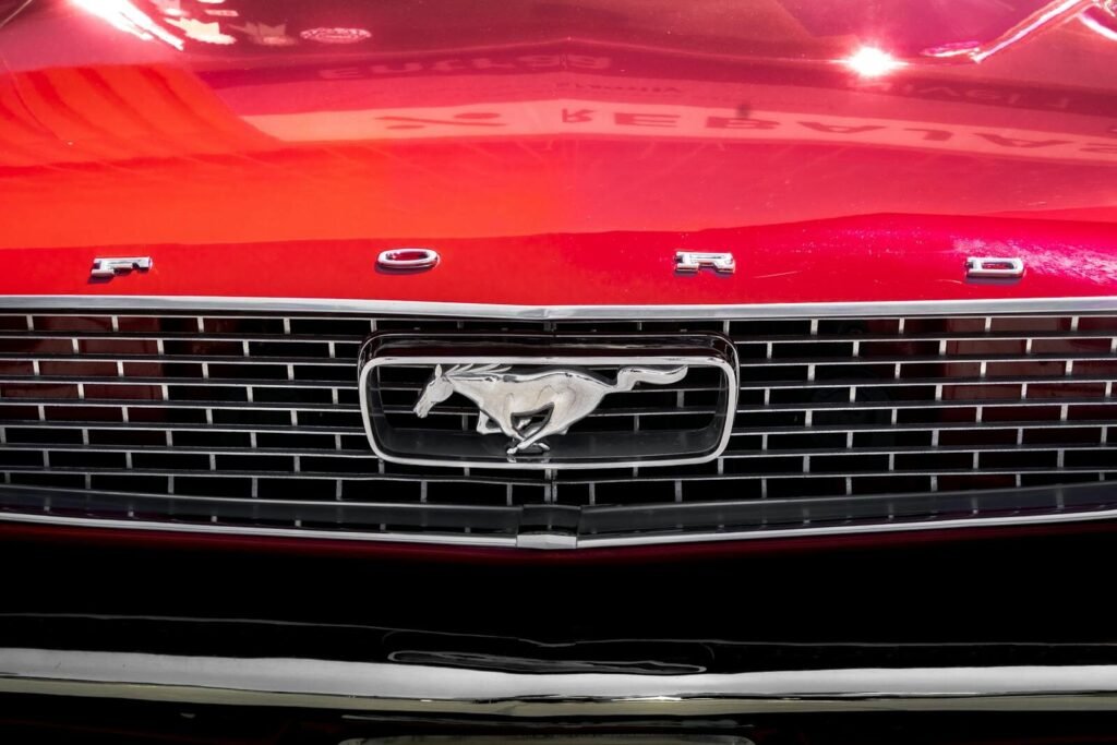 Detailed close-up of the iconic grille of a vintage red Ford Mustang.