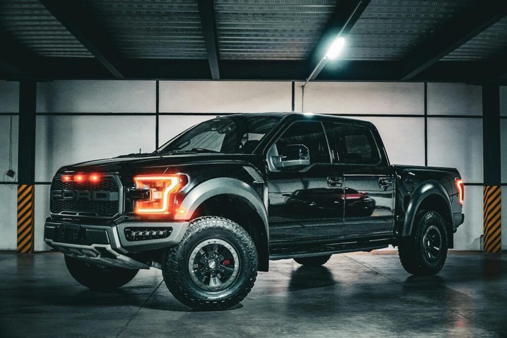 Bold black pickup truck with illuminated lights in an industrial garage.