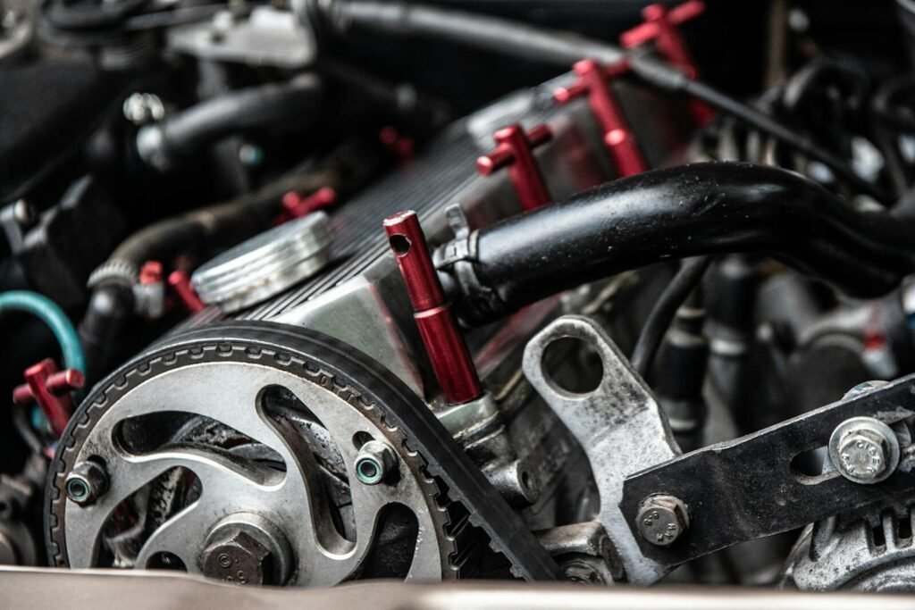Closeup of black thick hosepipes and timing belt on metallic detail of car engine in daylight