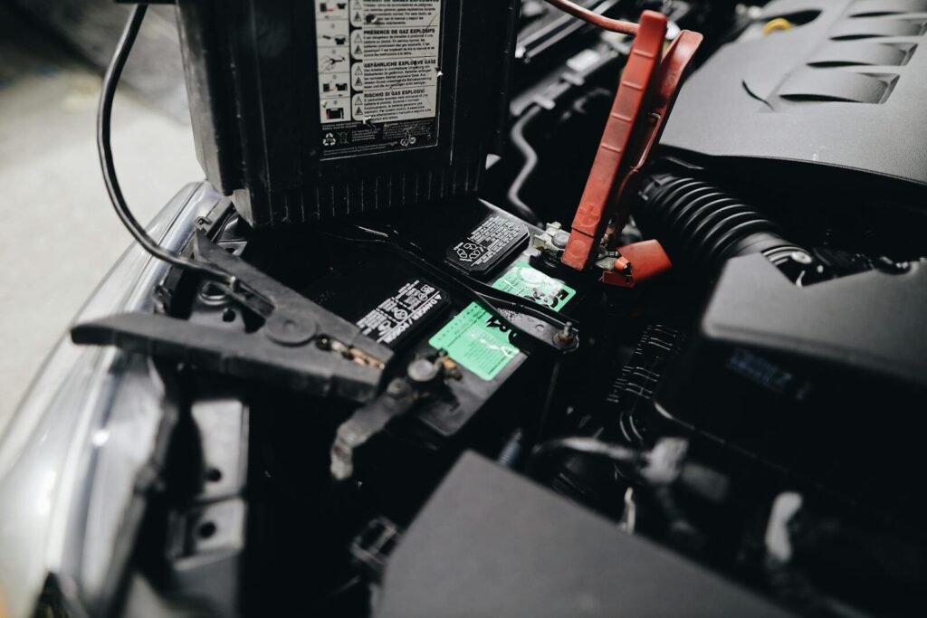 How to Choose the Right Car Battery (Without Guessing) 3 Detailed view of a car battery being jump-started with cables in an engine bay.