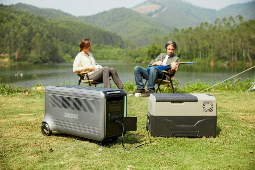 a couple of people sitting on a field next to a lake