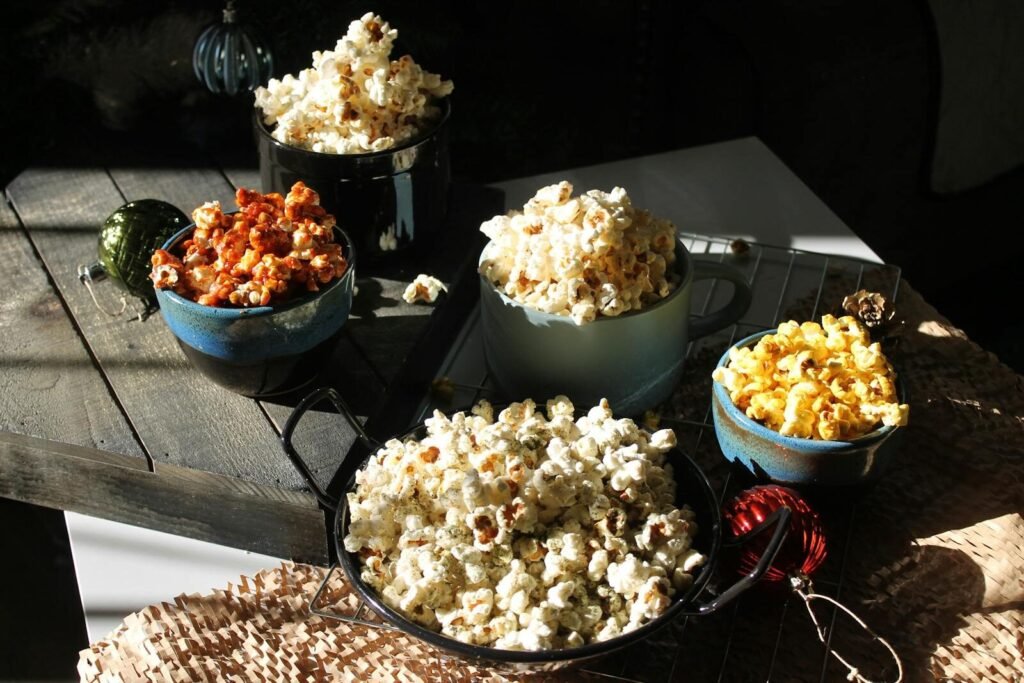 Assorted bowls of gourmet popcorn in a rustic, cozy setting, perfect for a snack lover.