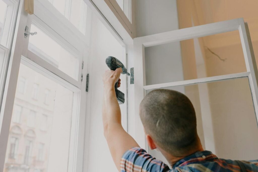 Everyday Fixes That Save Time Around the House 5 Back view of unrecognizable craftsman using cordless screwdriver and assembling window while screwing metal hinge during renovation works in apartment