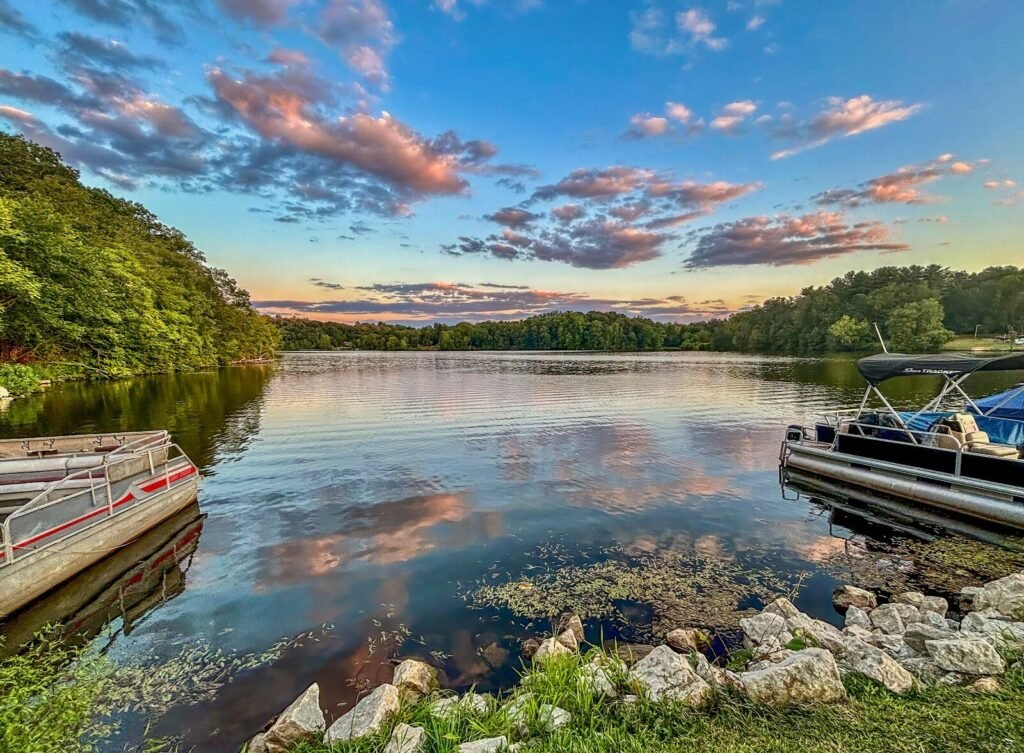 Boats docked on a serene lake at sunset.