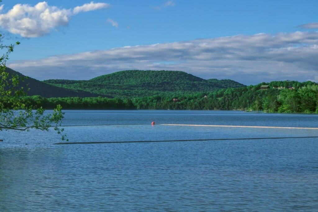 person in red shirt and black pants standing on white sand near body of water during