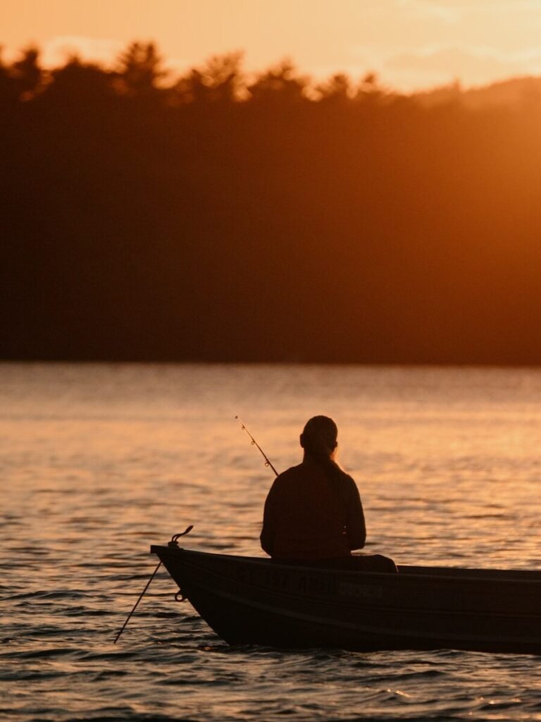 silhouette of man riding on boat during sunset