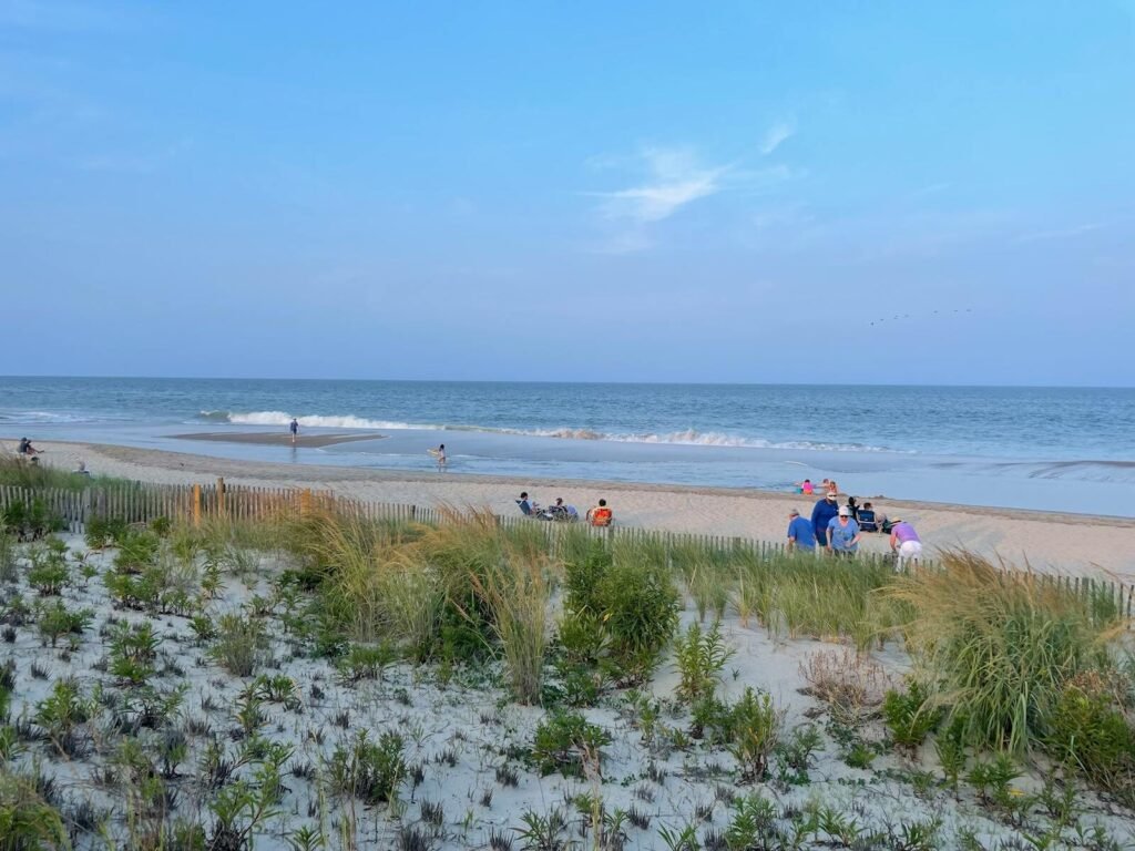 A beautiful beach scene with families enjoying the ocean and clear blue sky.