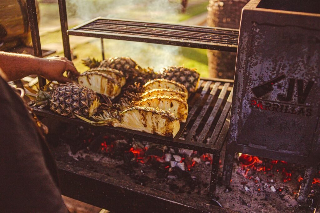Close-up of pineapples being grilled on a charcoal grill, showcasing tropical flavors.