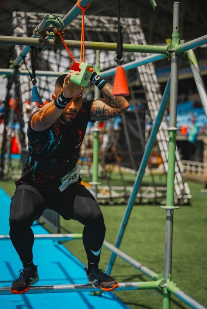 Outdoor Fitness Trends; Fit man tackling an aerial obstacle course, showcasing strength and agility in a competitive setting.